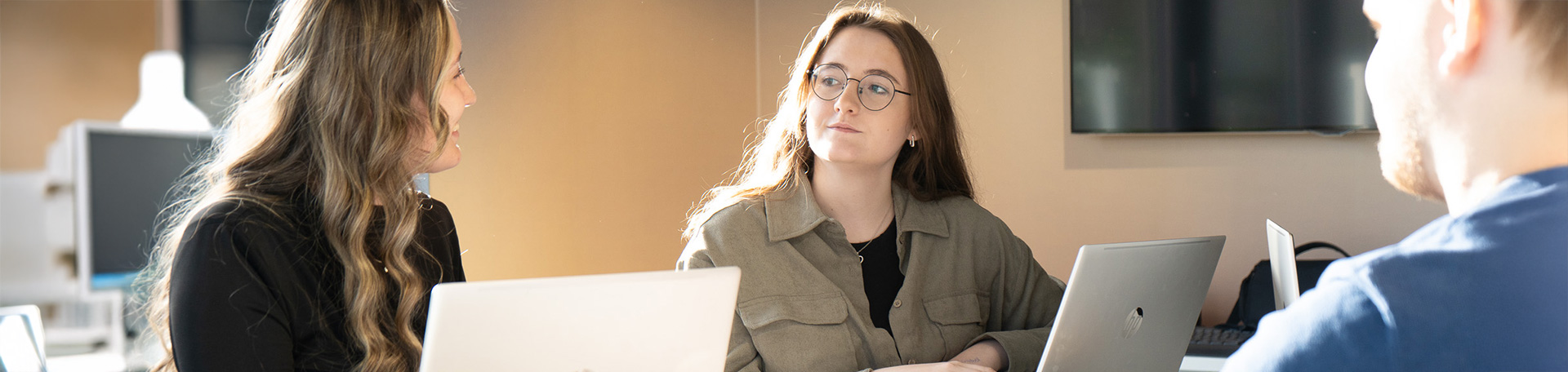 Zwei Frauen und ein Mann am Arbeitsplatz mit Laptops