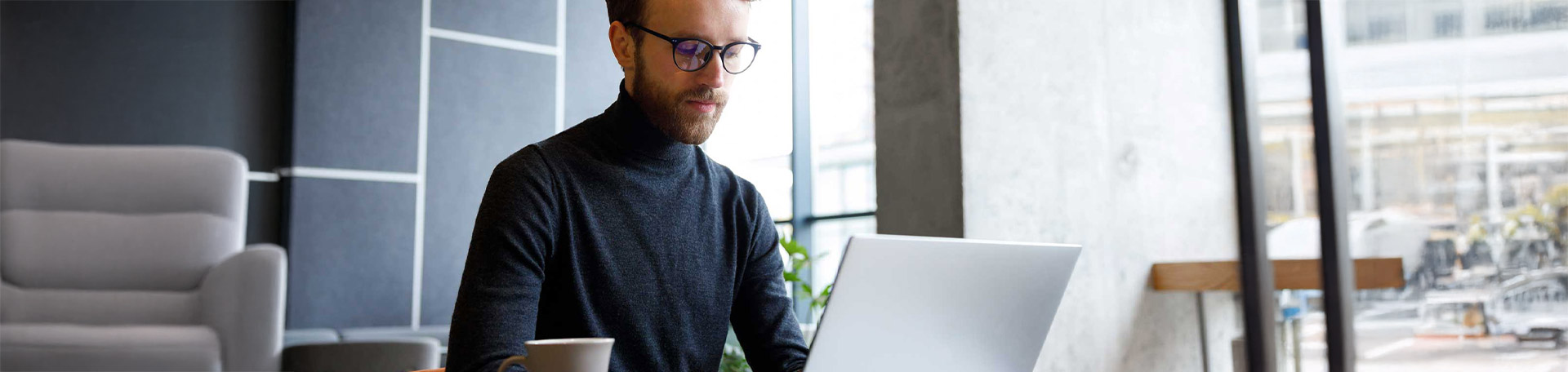 Mann mit Brille arbeitet am Laptop
